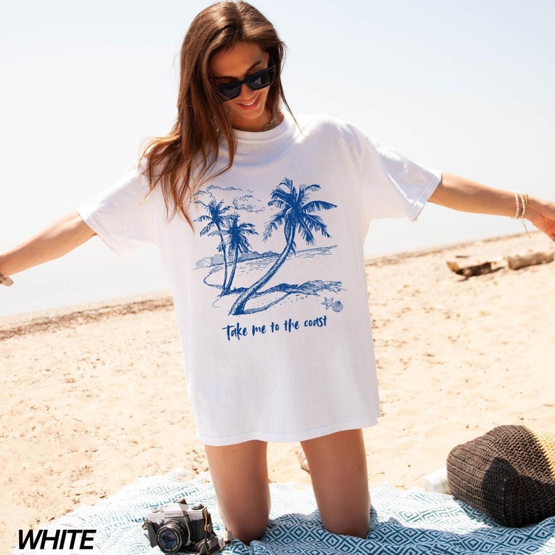 May include: White t-shirt with a blue graphic of palm trees and the text "Take me to the coast".