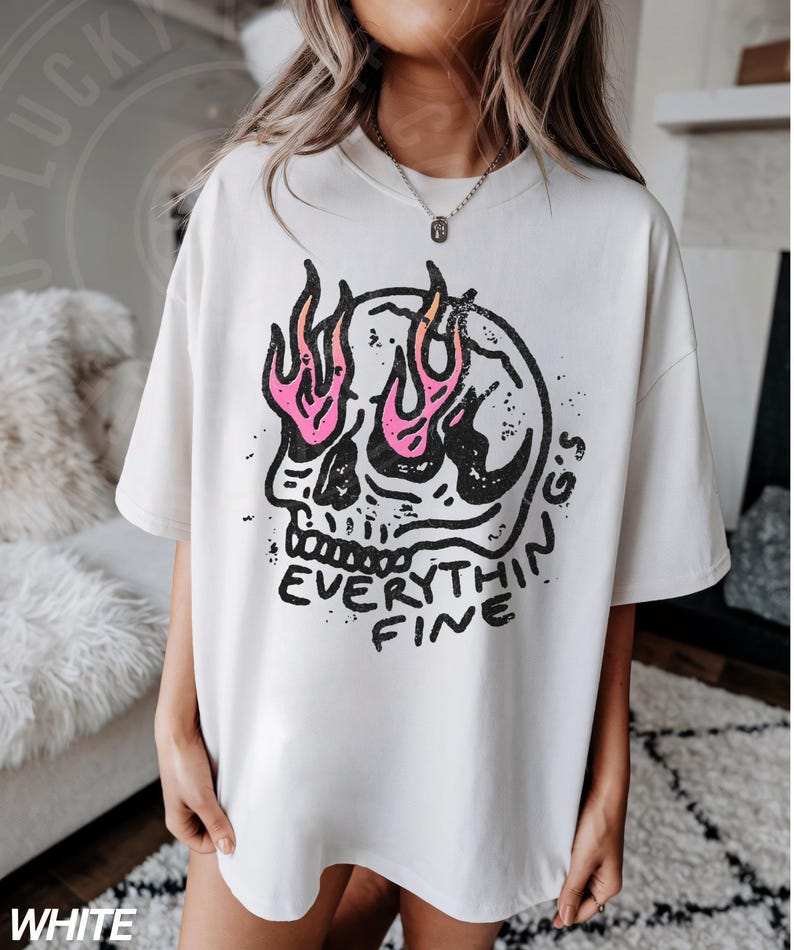 May include: White oversized t-shirt with a graphic print of a skull with flames for eyes and the text "Everything Fine".