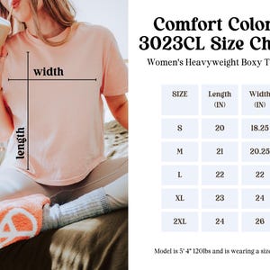 K&ouml;nnte beinhalten: Ein hellrosa, kastenf&ouml;rmiges T-Shirt mit einer Gr&ouml;&szlig;entabelle namens Comfort Colors 3023CL. Die Tabelle listet die Gr&ouml;&szlig;en S bis 2XL mit den entsprechenden L&auml;ngen- und Breitenma&szlig;en in Zoll auf, von 20 bis 24 Zoll L&auml;nge und 18,25 bis 26 Zoll Breite.