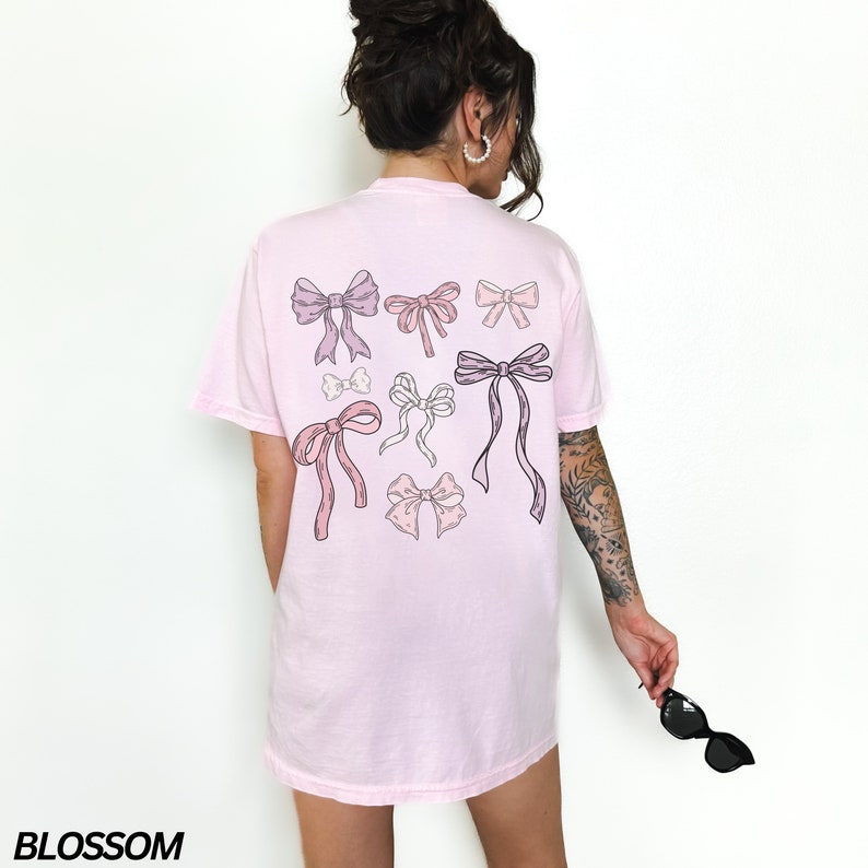 May include: A pink t-shirt with a graphic of multiple pink and purple bows on the back.