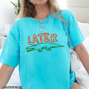 May include: A turquoise blue t-shirt with a green alligator and the word "LATER" in orange letters.