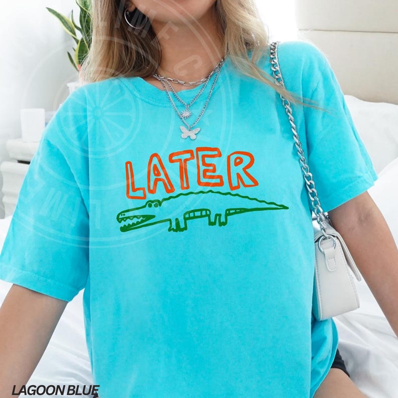 May include: A turquoise blue t-shirt with a green alligator and the word "LATER" in orange letters.