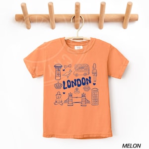 May include: A bright orange t-shirt with a blue graphic of London landmarks, including a double-decker bus, a red telephone box, Big Ben, and the words "LONDON".