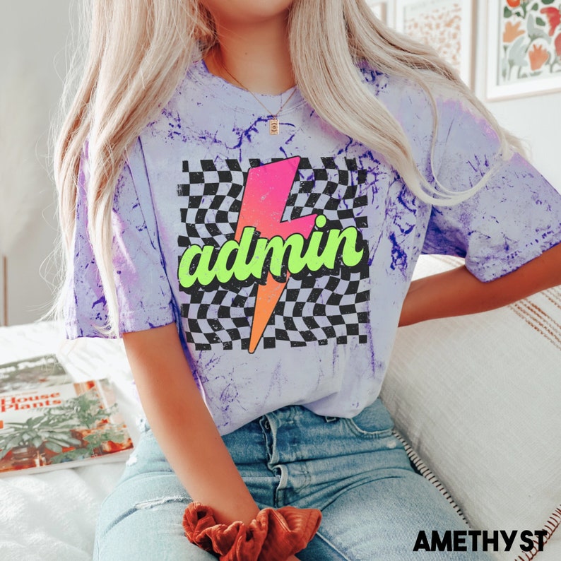 May include: A purple tie-dye t-shirt with a black and white chequered background and a pink and orange lightning bolt with the word "admin" in green letters.