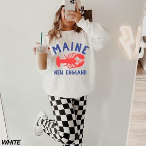 May include: White sweatshirt with a red lobster graphic and the text "Maine New England".