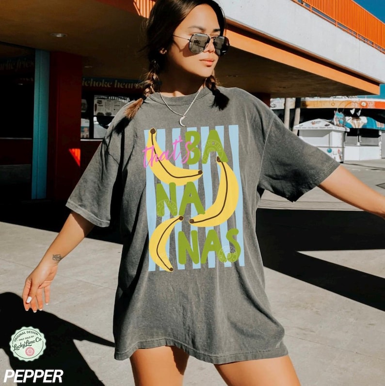 May include: Dark grey t-shirt with a graphic design featuring yellow bananas and the text "That's BANANAS" in a vertical layout. The shirt has a vintage, washed look.