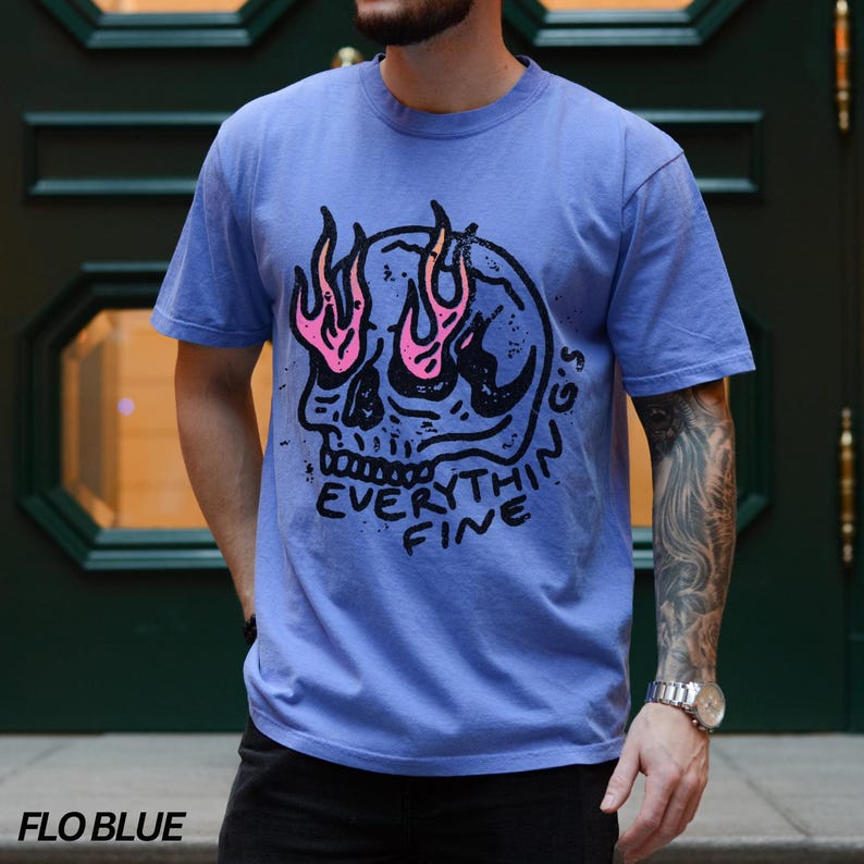 May include: A blue t-shirt with a skull graphic and the text "Everything's Fine" printed on the front. The skull has flames coming out of its eyes.