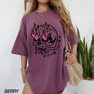 May include: Purple oversized t-shirt with a graphic of a skull with flames for eyes and the text "Everything's Fine".