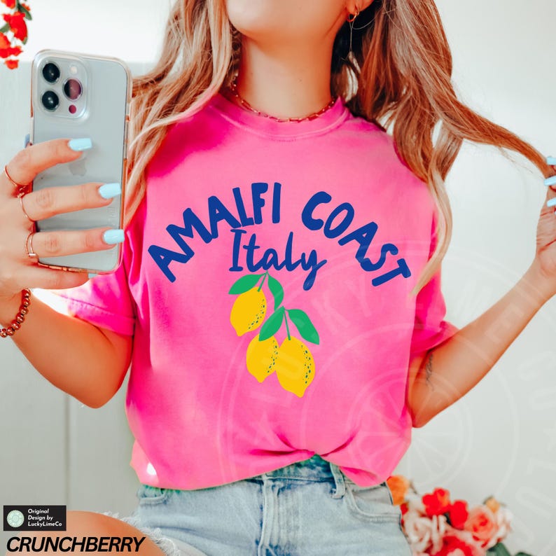 K&ouml;nnte beinhalten: Ein pinkfarbenes T-Shirt mit einer blauen Grafik, auf der "Amalfi Coast Italy" mit einem Zitronendesign steht.