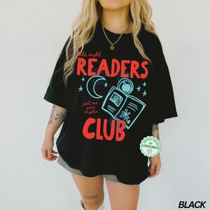 May include: Black oversized t-shirt with a graphic design for a book club. The design features the words "Late Night Readers Club" in red and blue, with a crescent moon, stars, and an open book illustration.