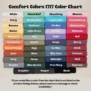 May include: Color chart featuring a variety of Comfort Colors 1717. The chart displays a spectrum of colors, including white, pink, blue, green, and brown. Each color is labeled with its name, such as "Blossom," "Chambray," and "Black."