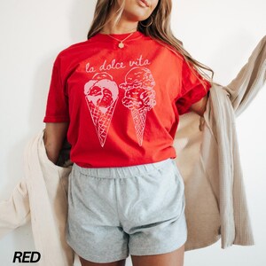 Op de afbeelding: Rood T-shirt met de tekst "la dolce vita" en een afbeelding van drie ijshoorns.
