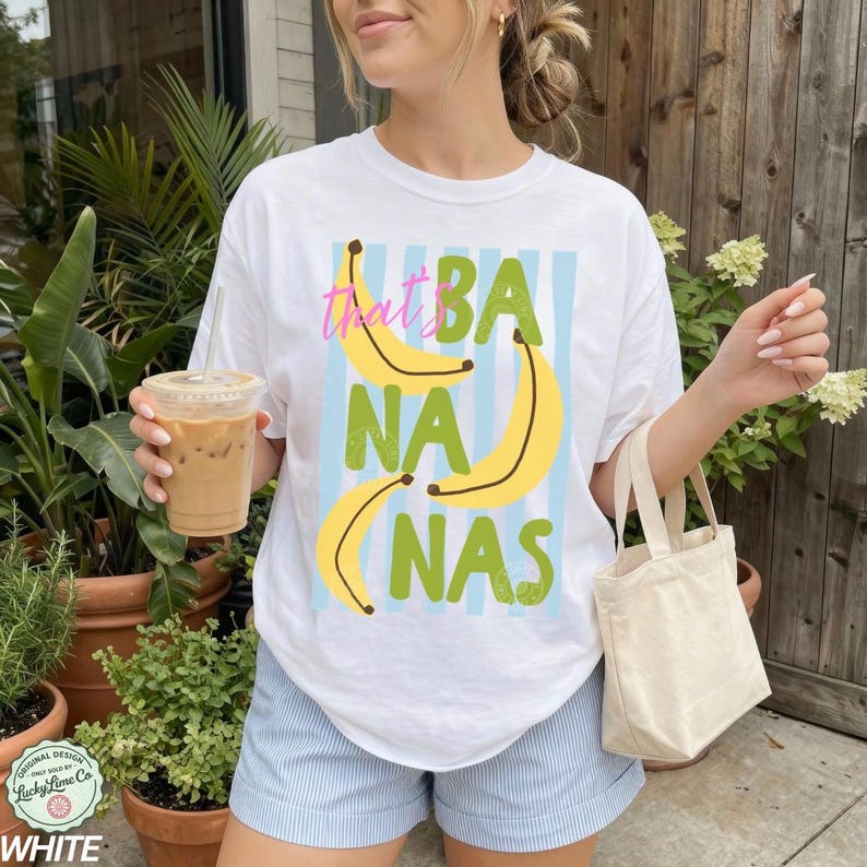 May include: White t-shirt with a playful "That's Bananas" graphic. The design features yellow bananas and green text on a light blue striped background. The shirt is part of a casual summer clothing collection.