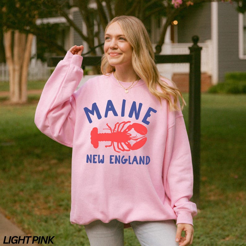 May include: A light pink sweatshirt with a blue and red graphic of a lobster and the text "Maine New England".