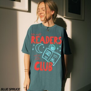 May include: Blue spruce t-shirt with the words "late night READERS CLUB" in red and light blue. The design includes a crescent moon, stars, and an open book. The text "and one more chapter" is also included.