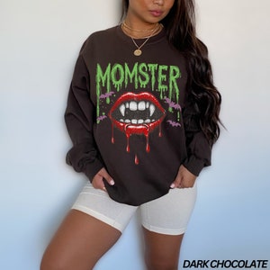 May include: A dark chocolate brown sweatshirt with a graphic print of a dripping red mouth with fangs and the word "MOMSTER" in green dripping letters.
