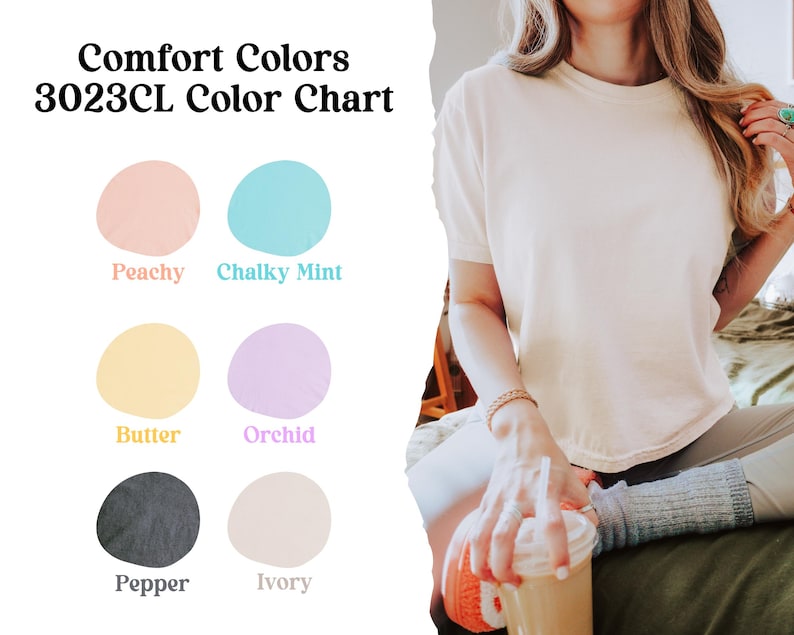 K&ouml;nnte beinhalten: Eine Comfort Colors 3023CL Farbkarte mit sechs kreisf&ouml;rmigen Farbmustern, beschriftet als Peachy, Chalky Mint, Butter, Orchid, Pepper und Ivory. Daneben ist ein kurz&auml;rmeliges T-Shirt in Elfenbein zu sehen, das von einer Person getragen wird.