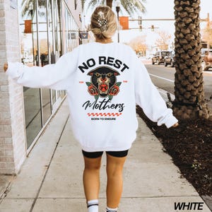 May include: White sweatshirt with a black panther graphic and the text "No Rest For The Mothers Born To Endure".