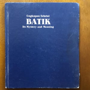 Könnte beinhalten: Ein blaues Buch mit dem Titel "Ungkapan Sehelai BATIK Its Mystery and Meaning" in weißer Schrift.