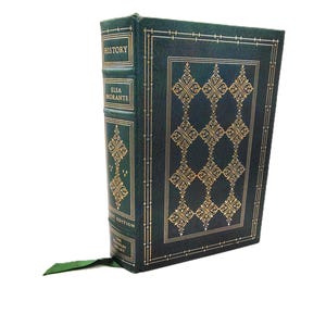 May include: A hardcover book titled "HISTORY" by Elsa Morante. The book has a dark green cover with gold decorative patterns and text. A green ribbon bookmark extends from the top of the book.