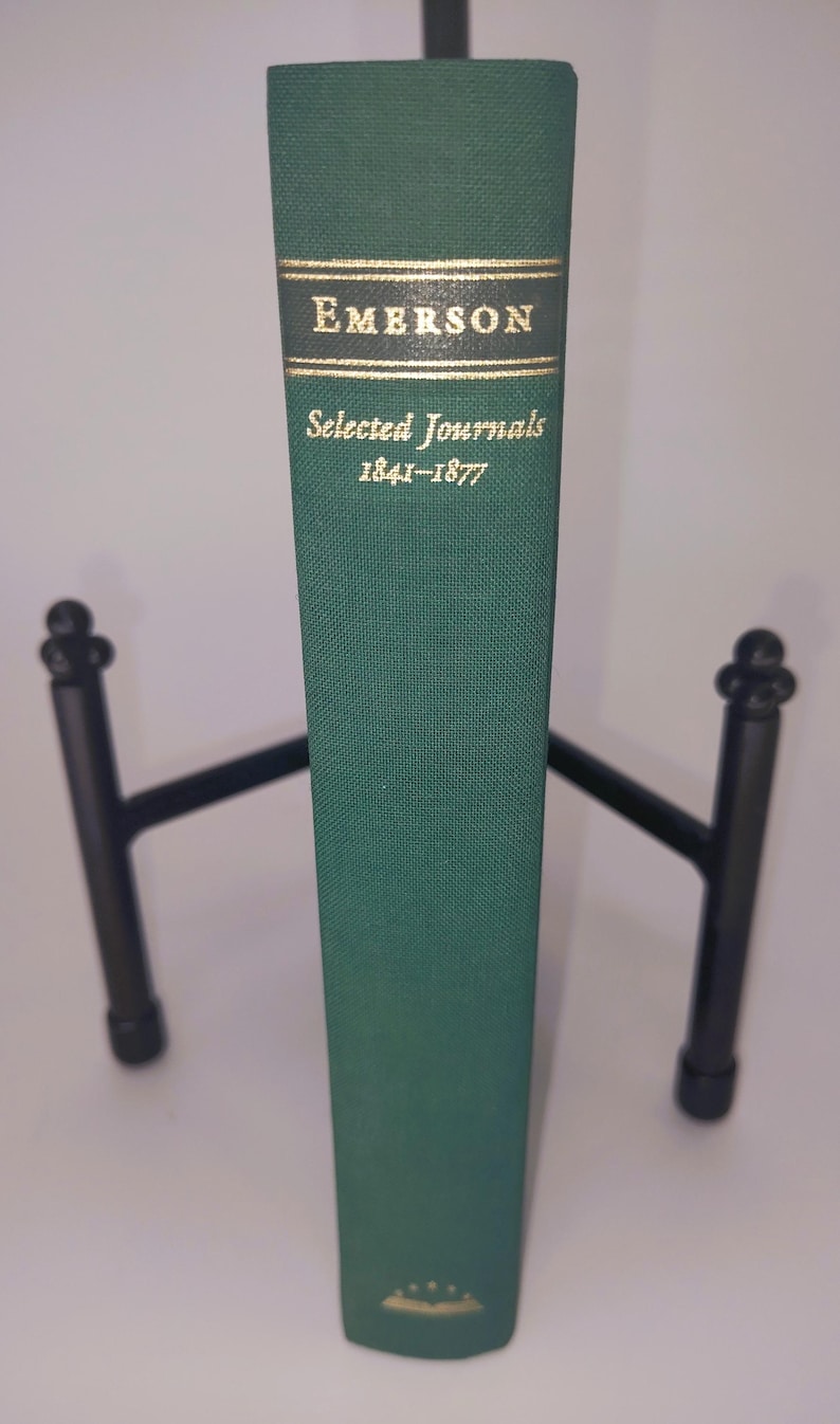 K&ouml;nnte beinhalten: Ein gr&uuml;nes Hardcover-Buch mit goldenen Lettern auf dem R&uuml;cken. Der Titel lautet "EMERSON Selected Journals 1841-1877".