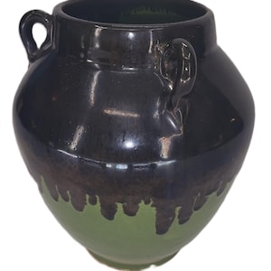 May include: Black ceramic vase with a green glaze dripping down the sides. The vase has two handles.