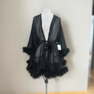 May include: A black sheer robe with a satin sash and feather trim. The robe is on a white mannequin.