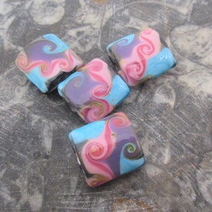 May include: Five square-shaped glass beads with a swirling pattern of pink, blue, and purple. The beads have a glossy finish.
