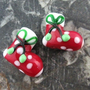 May include: Two red and white polka dot glass Christmas stocking ornaments with green bows and green beads.
