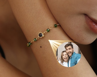 May include: Gold-toned bracelet with green beads and a central dark stone. The bracelet is worn on an arm, with a small photo of a couple in a circle. The brand name "myLoveSparks" is at the bottom.