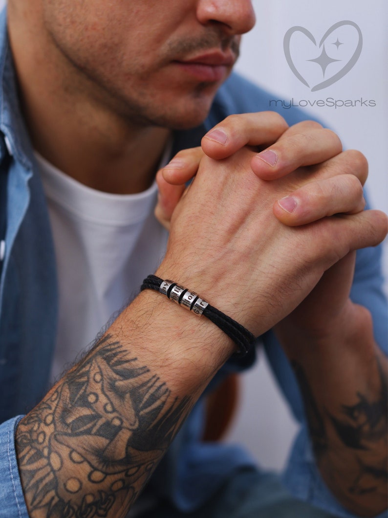 May include: Black braided bracelet with silver beads that spell out 'BEST'.