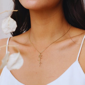 May include: A gold chain necklace with a delicate pendant featuring the word "Graduate" in cursive script. The pendant is a graduation cap.