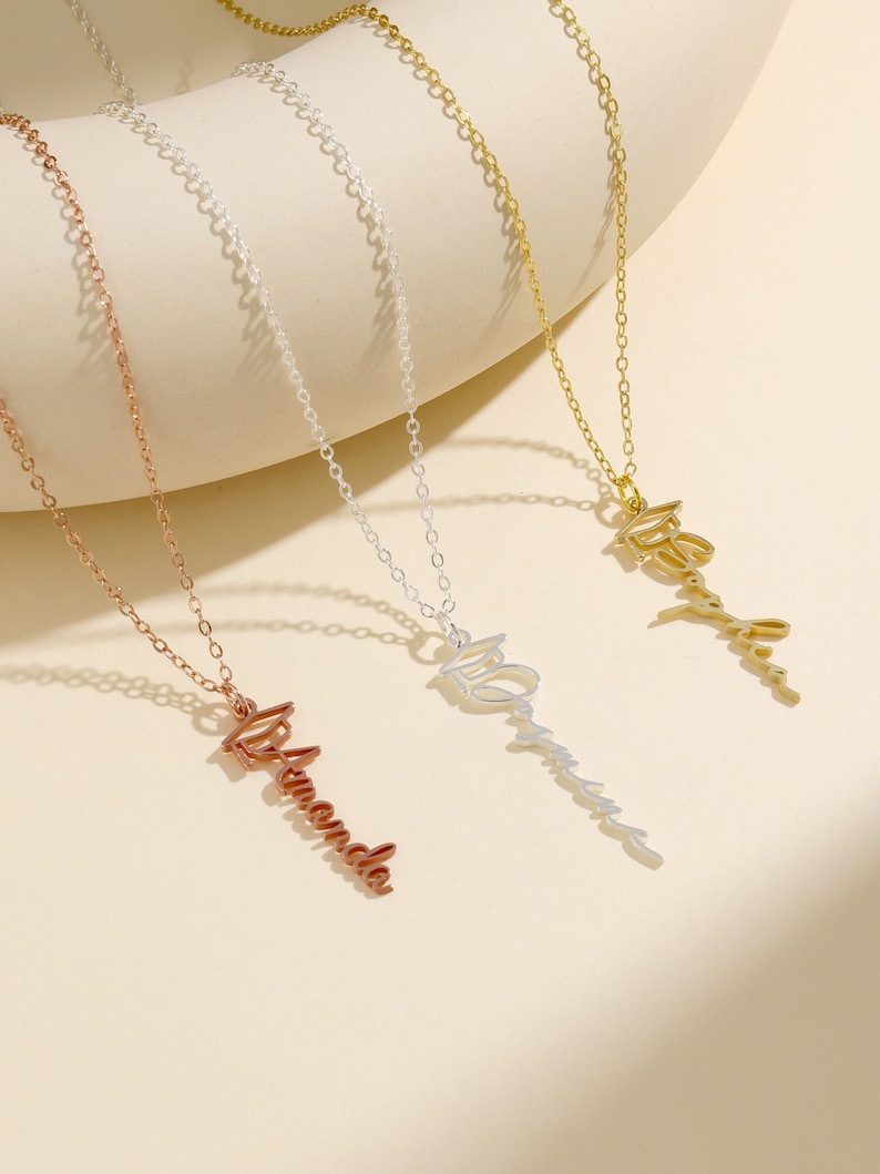 May include: Three gold necklaces with personalized name pendants. The necklaces are on a white background. The names on the pendants are "Amanda", "Olivia", and "Ashley".