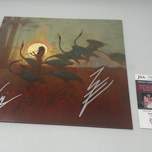 May include: A signed print of a painting depicting a woman playing a flute in a forest with birds flying around her. The print is signed by two people, one in silver and one in black ink.