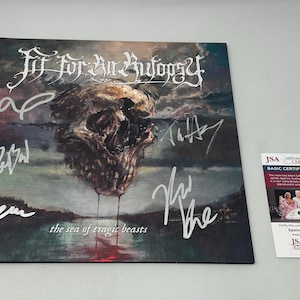 May include: A signed album cover for "Fit for an Autopsy" featuring a skull over a dark landscape. The album title is "the sea of tragic beasts". Includes a JSA authentication sticker.
