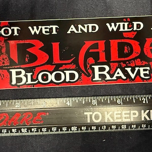 May include: Red and black sticker with the text "I got wet and wild at The Blade Blood Rave".
