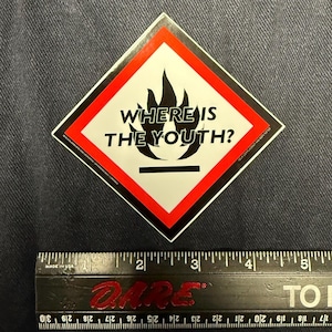 May include: A red and black diamond-shaped warning sign with a black flame and the text "WHERE IS THE YOUTH?" printed in black.