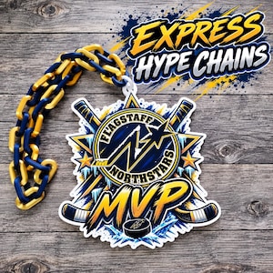 Peut inclure: Une chaîne décorative en plastique aux maillons alternés bleu marine et or, fixée à un médaillon circulaire arborant le logo Flagstaff Northstars, des crosses de hockey croisées et le texte MVP en lettres jaunes sur fond bleu et blanc.