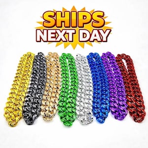 Puede incluir: Una colección de collares de cadena gruesos y coloridos en oro, negro, bronce, verde, plata, azul, morado y rojo. Los collares tienen un diseño audaz. El texto "SHIPS NEXT DAY" se muestra en la parte superior.