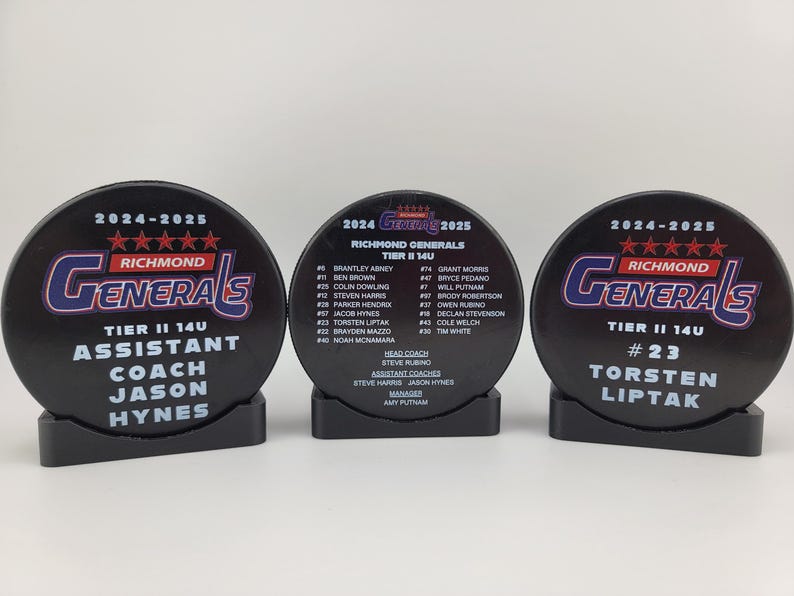 May include: Three black hockey pucks with white text and logos. The left puck says "2024-2025 Richmond Generals Tier II 14U Assistant Coach Jason Hynes". The middle puck has a roster of players and coaches for the Richmond Generals Tier II 14U team. The right puck says "2024-2025 Richmond Generals Tier II 14U #23 Torsten Liptak".
