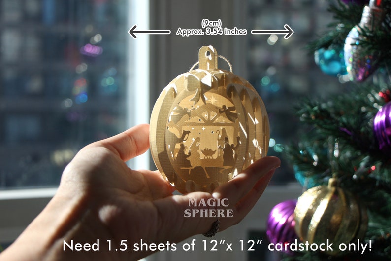 May include: A wooden Christmas ornament with a nativity scene inside. The ornament is 3.54 inches in diameter and requires 1.5 sheets of 12x12 inch cardstock to make. The ornament is labeled "Magic Sphere".