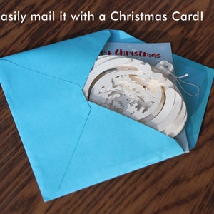 May include: A blue envelope with a white Christmas ornament and a card that says "Merry Christmas" inside.
