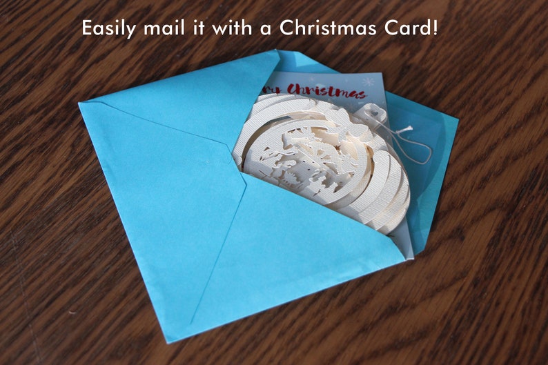 May include: A blue envelope with a white Christmas ornament and a card that says "Merry Christmas" inside.