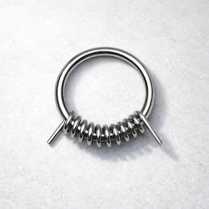May include: A silver-colored metal ring with a coiled spring design. The ring is circular with a thick band, and the spring is wrapped around a portion of the ring. Two straight metal rods extend from the spring.
