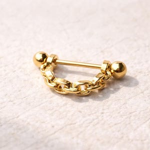 May include: A gold-colored body piercing jewelry piece. The jewelry features a straight barbell with a chain design. The barbell has a ball on each end. The chain is made of small, interconnected links.