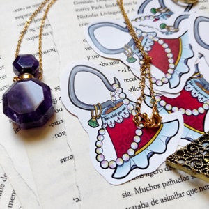 May include: A gold chain necklace with a purple glass bottle pendant and a sticker of a red and white bell with the text "Take what you can" on it.