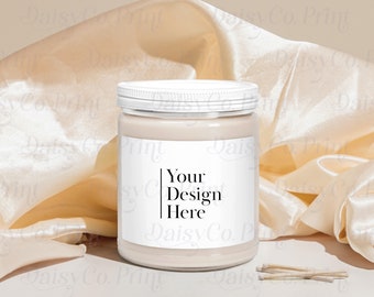 Pode incluir: Um frasco de vela branco com um recipiente de vidro transparente e um rótulo branco. O rótulo tem o texto "Your Design Here". O frasco de vela está sentado em uma superfície branca com um pedaço de tecido bege atrás.