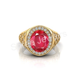 May include: A gold ring with a large oval ruby surrounded by a halo of smaller diamonds. The ring has a detailed design on the band.