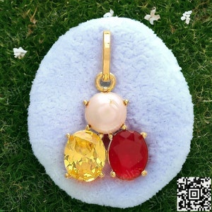 May include: Gold pendant with three gemstones: a round white pearl in the center, a yellow oval gemstone on the left, and a red oval gemstone on the right.