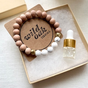 May include: A wooden and white stone bracelet with gold accents, packaged in a box with a small bottle of essential oil. The box has a label that says "wild oak essentials".
